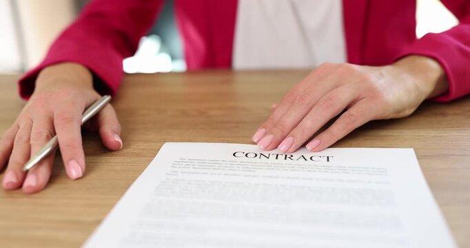 Businesswoman offers contract document sheet to sign holding metal pen at wooden desk. Businesswoman shows agreement for signification in office
