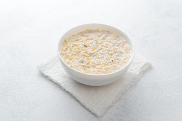 Bowl of creamy oatmeal porridge on white towel background