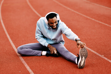 Happy man stretching leg on running track