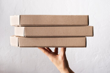 Caucasian male hands hold three pizza boxes side view with copy-space