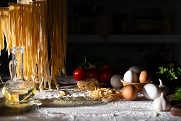 Homemade noodles hanging on wooden dryer rack over messy kitchen table background low angle front view