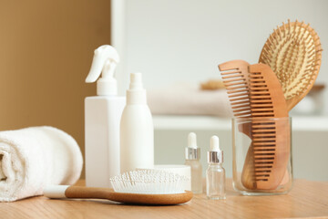 Set of cosmetic products, clean towel, hair brushes and combs on wooden table in room