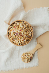Wooden bowl and spoon with granola on white fabric background