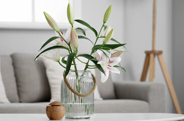Vase with beautiful lily flowers and aroma oil diffuser on coffee table in living room, closeup