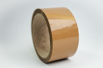 Moving day essential. A brown tape roll for packing household items into cardboard boxes, symbolizing relocation and a new home.