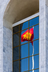 National Flag of Kyrgyzstan waving, reflected in glass windows of modern building
