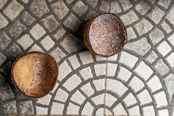 Coconut shell halves rest on patterned floor tiles, contrasting organic texture with geometric design. Perfect for food, rustic lifestyle, or recycling and eco-friendly product visuals