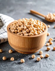 Light beige chickpeas in a light wooden bowl on a mottled gray surface