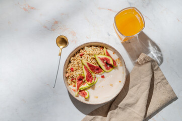 Natural yogurt with granola, figs and honey in a bowl on a marble background