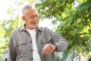 Fototapeta premium Portrait of senior man checking time in park