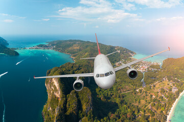 Obraz premium Passenger jet plane flying over picturesque island blue ocean in purity destination sea beach for summer holiday vacation traveling.