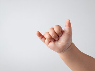 Child's hand making shaka gesture indoor setting close-up image neutral background playful concept for family and friendship