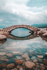 Obraz premium A serene stone bridge arches over calm waters, reflecting the tranquil sky and surrounding landscape, creating a picturesque scene ideal for travel features, nature blogs, or calming visuals,
