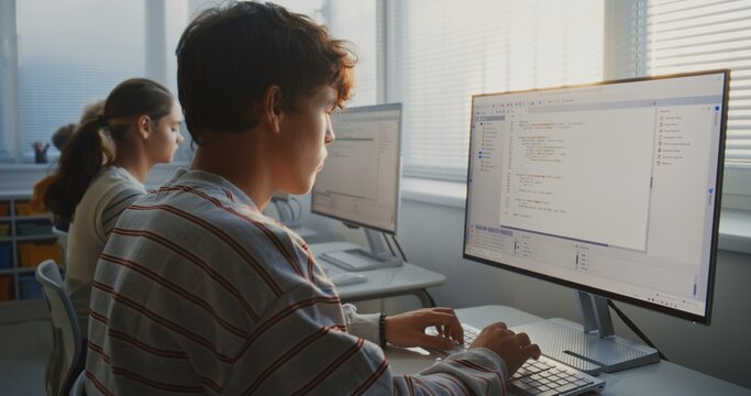 Young People Study Programming in Bright University Classroom. Students Type Computer Code on Monitors, Practicing Teamwork, Software Development, and Essential Digital Skills For Future. Static Shot.