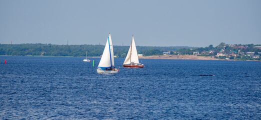 Fototapeta premium Two sailboats on lake near coastal town on a summer day