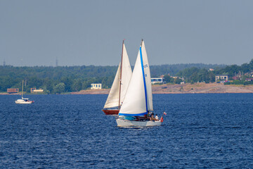 Two sailboats on lake near coastal town on a summer day
