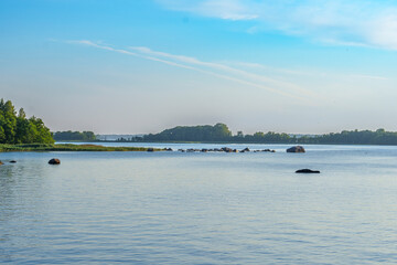 Peaceful lake landscape with rocky shoreline and distant forest