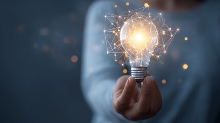 A person holds a bright, glowing light bulb, a symbol of innovation, creativity, and new ideas. The image portrays the essence of intellectual discovery, inspiration, and the power of imagination.