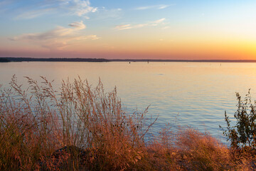 Peaceful lake at sunset with calm water and grasses in foreground
