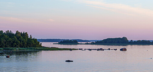 Calm lake with islands and pastel sky at sunset