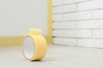 Roll of masking tape on floor near masked baseboard, closeup