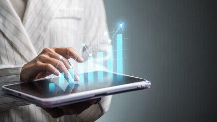 Business analyst using tablet with rising bar chart and growth line