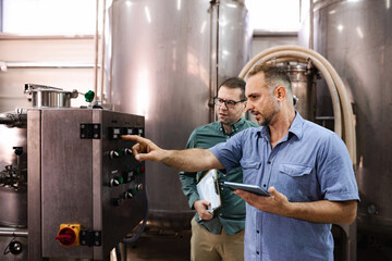 Men operating industrial control panel in brewery factory