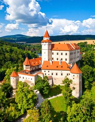 Obraz premium Panoramic view of a medieval castle nestled amidst lush greenery and rolling hills