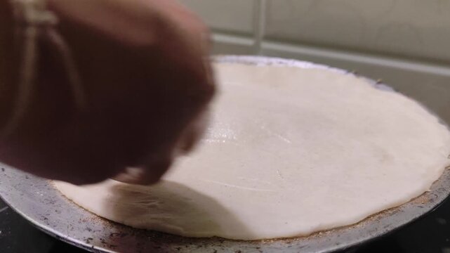 Closeup video of making or roasting traditional Indian jowar roti on a pan over a gas stove with selective focus.