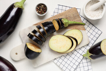 Cut fresh eggplants, spices and cutting board on white background, closeup