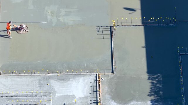 Construction Worker Smoothing Wet Concrete with Power Trowel Overhead