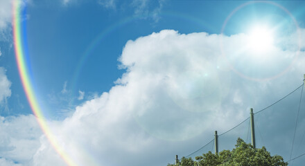 夏の晴天、青空に流れる積乱雲ふわふわの入道雲と輝く太陽のレンズフレア 夏・夏休み・行楽・バカンス・アウトドア・キャンプ・天気・台風一過・紫外線・日焼け 秋・秋晴れ