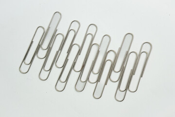 A simple silver metal paper clip (or a collection of paper clips) on a clean white background. Essential office stationery for organizing documents