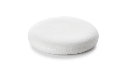 A fluffy white circular pad rests on a plain white surface casting a soft shadow