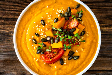 Pumpkin cream soup on wooden table. Top view