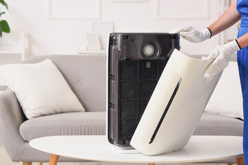 Female technician changing dirty air purifier filter at home