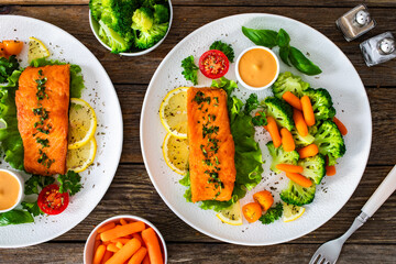 Fried salmon steak with boiled broccoli and mini carrots and mayonnaise on wooden table. Top view
