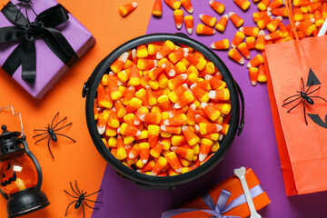 Composition with pot of tasty candy corns, Halloween decorations, gift boxes and shopping bag on color background