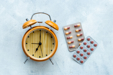 Medical treatment pills and vintage alarm clock, top view. Time to take medicine concept
