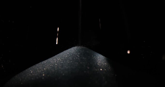 White sugar slowly falls into transparent glass flask creating small pile on bottom. Grains of sugar descend into glass container in steady flow