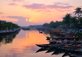 A stunning sunrise in Hoi An Ancient Town, Vietnam. A peaceful scene with a tranquil river and boats. A city over 400 years old with East Asian architecture, a famous tourist destination.