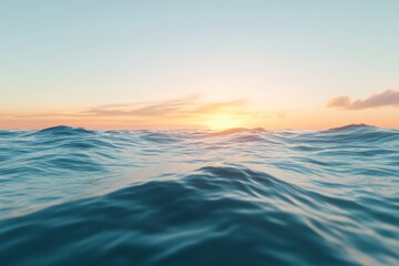 Fototapeta premium Ocean surface with gentle waves reflecting the warm golden light of a calm sunrise. The sky shows a soft color gradient