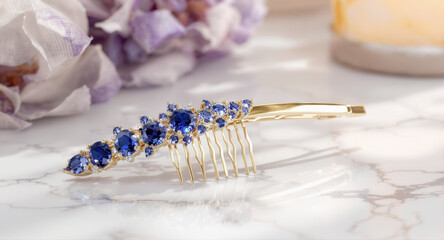 Elegant blue sapphire hair comb beautiful jewelry accessory. Romantic gold and gemstone decor on marble surface