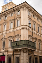 Historic European building facade with ornate windows and green enclosed balcony in Rome