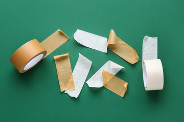 Rolls and strips of masking tape on green background