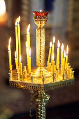 Vertical photo of a church pedestal with candles burning on it