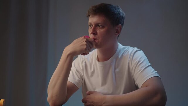 Portrait of relaxed young man using electronic cigarette, exhaling vape smoke, reflecting on health implications and risks of vaping and nicotine addiction, considering alternative habits, slow motion