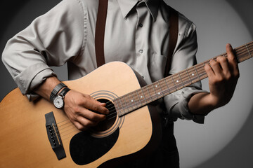Fototapeta premium Young man playing acoustic guitar on grey background