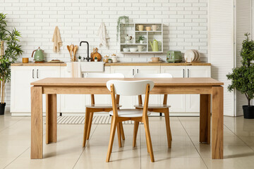 Interior of stylish kitchen with dining table, white counters and sink