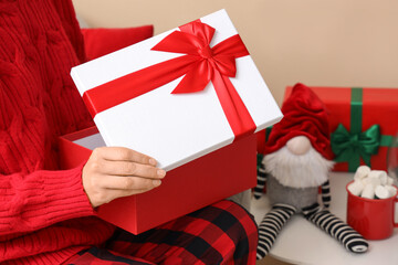 Woman opening beautiful Christmas gift box at home, closeup